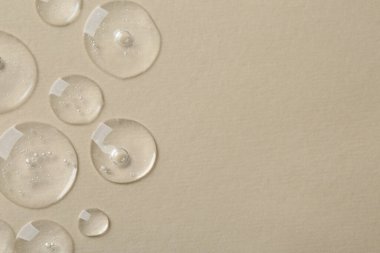 Bej arka planda kozmetik serumu damlaları, üst manzara. Metin için boşluk