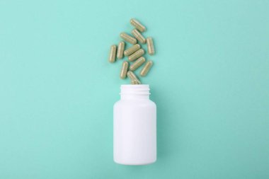 Turkuaz arka planda şişe ve vitamin kapsülleri, üst görünüm