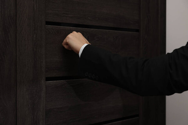 Collector knocking on door indoors, closeup view