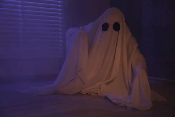 Creepy ghost. Woman covered with sheet near window in color lights, space for text