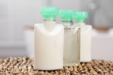 Hasır hasırın üzerinde küçük kozmetik ürünleri şişeleri bulanık arka plan, yakın plan