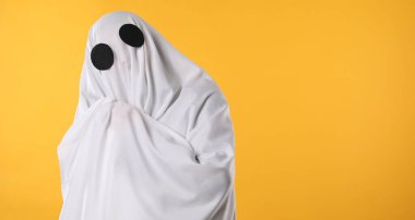 Ürkütücü hayalet. Sarı arkaplanda beyaz sayfa ile kaplı kişi, metin için boşluk