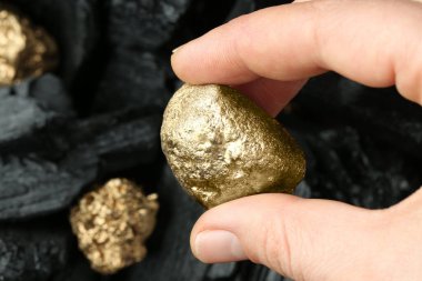 Bulanık arka planda altın külçesi tutan kadın, yakın plan. Metin için boşluk