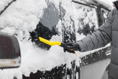 Dışarıdaki araba penceresinden kar temizleyen adam, yakın plan.