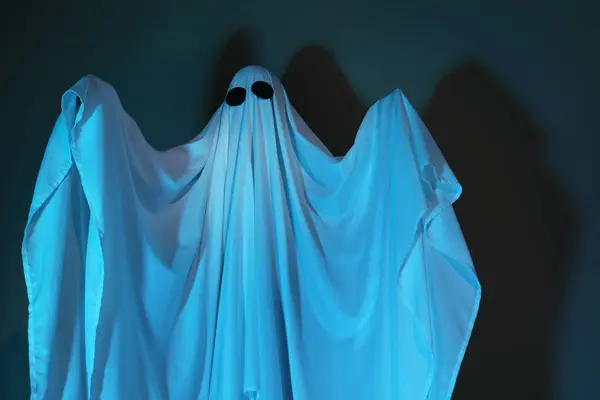 Creepy ghost. Woman covered with sheet in color light
