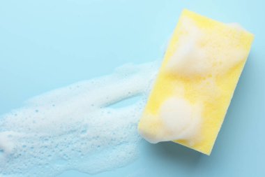 Açık mavi arka planda köpüklü sarı sünger, üst görünüm