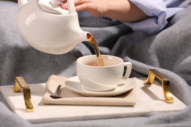 Kadın masadaki fincana aromatik çay dolduruyor, yakın plan.