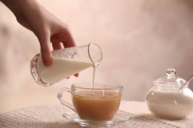 Kadın sütü aromatik çayla bardağa dolduruyor, yakın plan.
