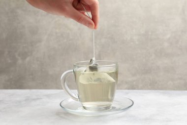 Çay demleniyor. Kadın ışık masasında fincana çay koyuyor, yakın plan.