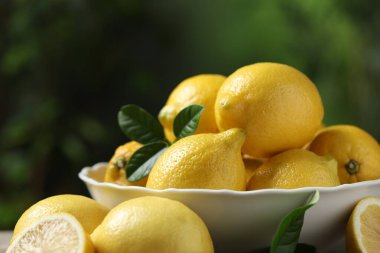 Taze limonlar ve yeşil yapraklar bulanık arka planda, yakın plan