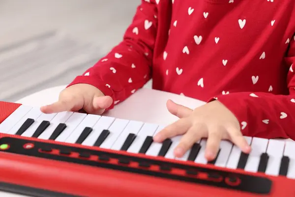 Little girl playing toy piano at home, closeup