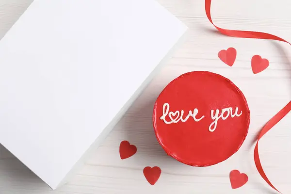 Bento cake with text Love You and takeaway packaging on white wooden table, flat lay