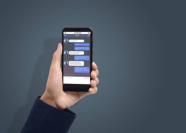 Arkadaşlarıyla mesajlaşan bir adam akıllı telefondan gri arkaplana mesaj yolluyor, yakın plan. Metin için boşluk