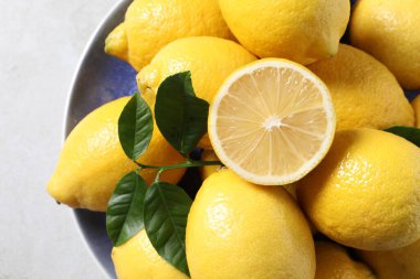 Taze limonlar ve yeşil yapraklar ışık masasında, üst manzara