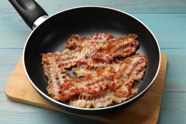 Lezzetli pastırmalar tavada dilimler mavi ahşap masada, yakın plan