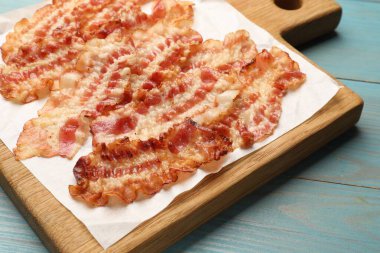 Lezzetli kızarmış domuz pastırması mavi ahşap masada, yakın plan.