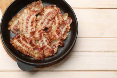 Beyaz ahşap masada tavada leziz pastırma dilimleri, üst manzara. Metin için boşluk