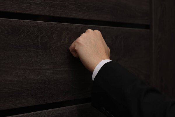 Collector knocking on door indoors, closeup view