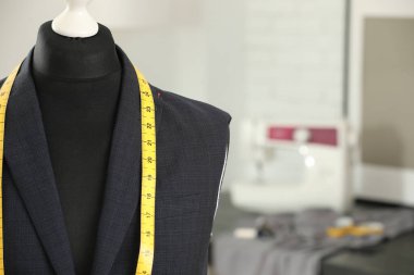 Tamamlanmamış ceketli manken ve terzi dükkanında mezura, yakın plan. Metin için boşluk