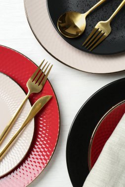 Beyaz ahşap masaya seramik tabaklar, çatal bıçak takımı ve peçete.