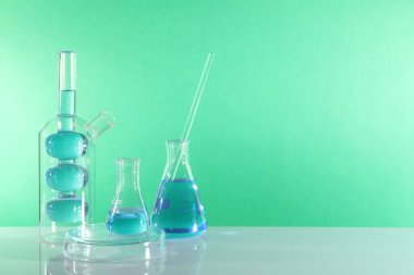 Laboratuvar analizi. Masada yeşil arkaplana karşı farklı cam eşyalar, metin için boşluk
