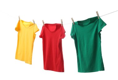 Beyaz arka planda çamaşır ipinde kuruyan farklı parlak tişörtler.