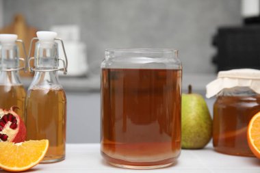 Ev yapımı mayalanmış kombu çayı ve mutfaktaki beyaz masada taze meyveler.