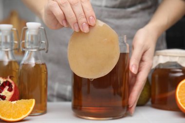 Beyaz masada ev yapımı mayalanmış kombu çayı yapan kadın, yakın plan.