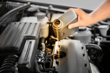 Adam araba motoruna motor yağı döküyor, yakın plan. Renk aksanı efekti