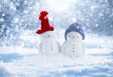 Karlı bir günde açık havada şapkalı sevimli kardan adamlar.