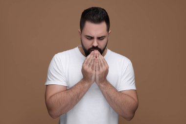 Kahverengi arka planda öksüren hasta bir adam. Soğuk belirtileri