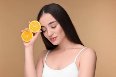 Bej arka planda turuncu parçaları olan güzel genç bir kadın.