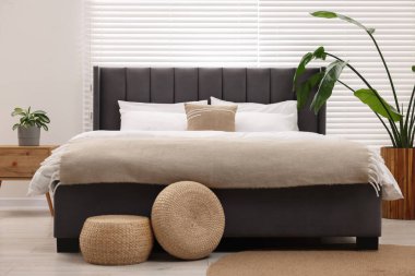 Şık bir yatak odasında büyük bir yatak ve bitkiler. İç tasarım