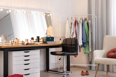 Makyaj odası. Ayna, sandalye ve elbise rafı olan şık bir makyaj masası.