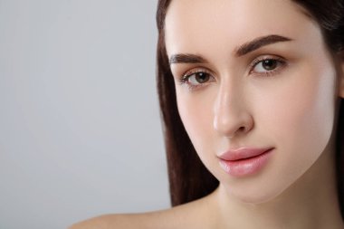 Açık gri arka planda sağlıklı cilde sahip güzel bir genç kadın, yakın plan. Metin için boşluk