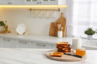 Kahvaltı mutfakta servis edilir. Çıtır tost, bal ve süt beyaz mermer masada. Metin için boşluk