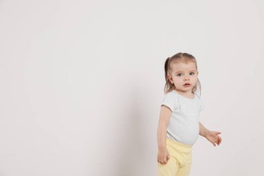 Evdeki beyaz duvarın yanında duran şirin küçük kız, mesaj için yer var.