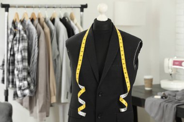 Tamamlanmamış ceketli manken ve terzi dükkanında mezura.