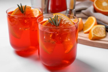Aperol spritz kokteyli, biberiye ve portakal dilimleri beyaz ahşap masa, yakın plan.