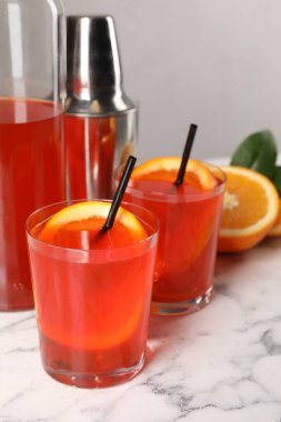 Aperol spritz kokteyli, portakal dilimleri ve pipetler beyaz mermer masada, yakın plan.