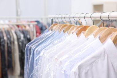 Kuru temizleme servisi. Plastik poşetlerdeki birçok farklı giysi kapalı yerlerde asılı, yakın plan.