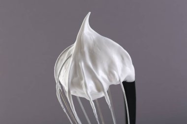 Gri arka planda krem şantili çırpma çırpma, yakın plan.