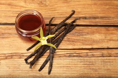 Aromatik vanilya özü, kapsüller ve çiçek ahşap masada. Metin için boşluk