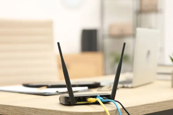 Modern Wi-Fi router on wooden table indoors