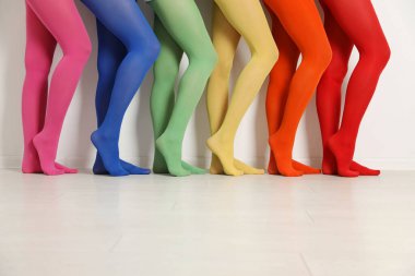 Beyaz duvarın yanında renkli tayt giyen kadınlar, yakın plan.