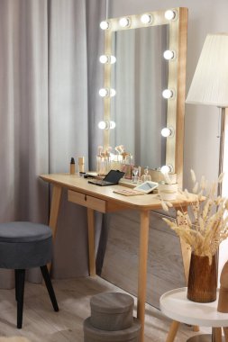 Makyaj odası. Soyunma masasında ampuller ve içeride sandalye olan şık bir ayna.