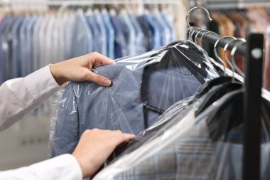 Kuru temizleme servisi. Kadın plastik torba içinde ceketini alıyor, kapalı mekandan, yakın plan.