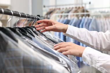 Kuru temizleme servisi. Kadın plastik torba içinde ceketini alıyor, kapalı mekandan, yakın plan.