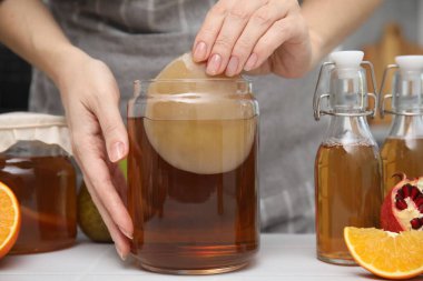 Beyaz masada ev yapımı mayalanmış kombu çayı yapan kadın, yakın plan.