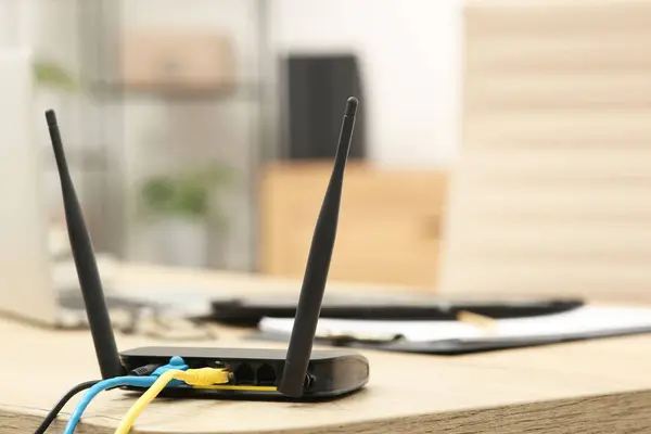 Modern Wi-Fi router on wooden table indoors, space for text